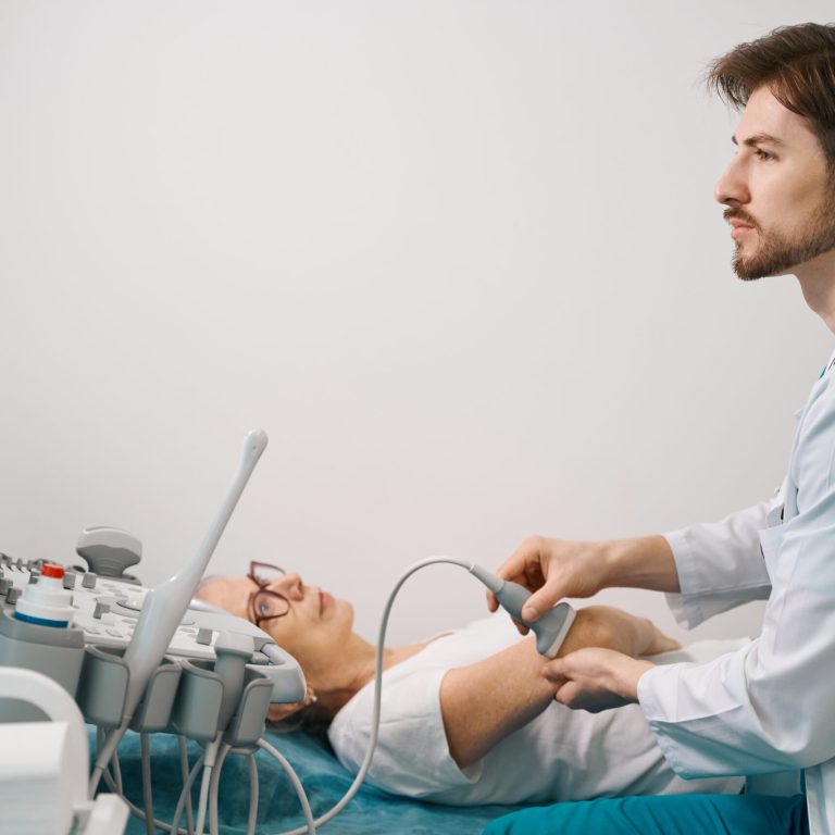 Woman patient on the examination of the joint on the ultrasound machine, doctor in medical uniform